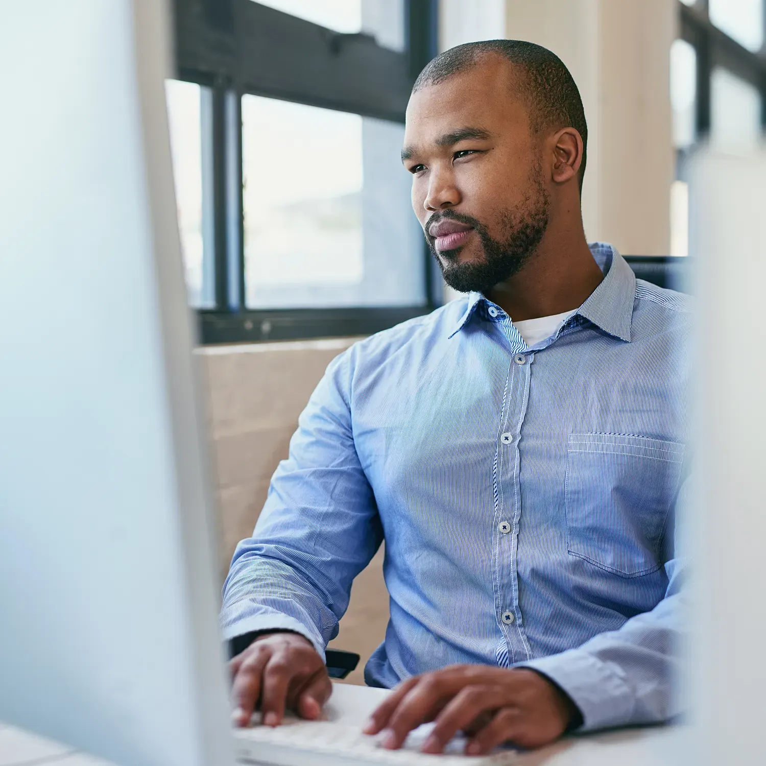 Homem negro concentrado trabalhando no computador no escrit&oacute;rio.